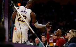 Bronny James, shown at right greeting his father LeBron during an NBA game on November 19, has been given medical approval to return to college basketball after suffering cardiac arrest during a July practice session, his family announced