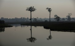 Smoke from illegal fires lit by farmers rises over a river in Careiro, Amazonas state, in September 2023