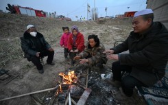 People huddle around a fire after an earthquake in northwest China’s Gansu province killed 131 people and damaged thousands of buildings