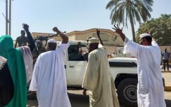 People displaced by the conflict in Sudan cheer as a Sudanese army truck driving by in the city of Gedaref