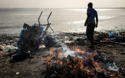 A man dumps waste into the ocean at Hann Bay