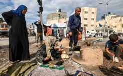 A woman bakes bread outside at a makeshift camp for displaced Palestinians in Rafah, in southern Gaza