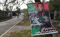 A poster with a picture of Pakistan's former prime minister Imran Khan (top) reading "Revenge of oppression with vote" hangs on a tree outside his residence guarded police in the Banigala area of Islamabad on February 1, 2024