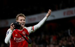 Martin Odegaard picks up a camera and takes pictures after Arsenal's win over Liverpool