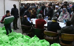 Returning officers wait to collect sacks of voting materials to polling stations from a distribution centre in Lahore, eastern Pakistan