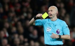 Premier League referee Anthony Taylor shows a yellow card