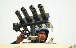 An Indian security officer stands atop an armoured vehicle at a roadblock during protests called by farmers on Tuesday