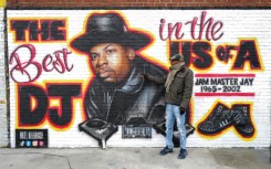 Local resident Jacob Rosthein poses before a mural paying tribute to late Run-DMC's Jam Master Jay in the Hollis neighborhood of Queens, as the trial into artist's murder gets underway