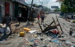 Haitians walk past a barricade March 20, 2024
