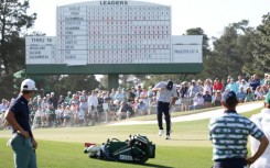 Bryson DeChambeau of the United States shields himself from the wind, blowing sand, on the 17th green at the Masters on Friday.