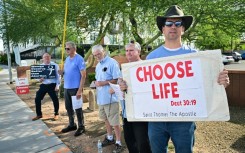 Matthew Engelthaler stands with a group of men from a local Catholic Church who gather "not to protest but to pray" for those arriving at Camelback Family Planning, an abortion clinic in Phoenix, Arizona 