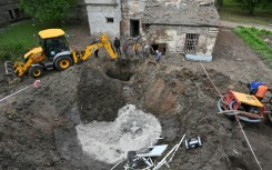 Utility workers operate next to a crater in the courtyard of a hospital in Kharkiv