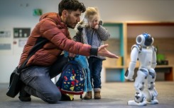 A father introduces his daughter to a robot called Nao in a Swiss creche  