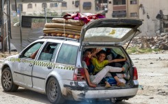 Children gesture as they sit in the back of a vehicle arriving at the Daraj quarter of Gaza City on May 11