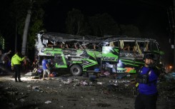 Officers check the debris and belongings of passengers after a bus crash on Java island