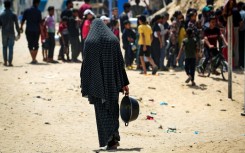 Palestinians walk past damaged and destroyed buildings in Gaza City