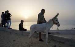 Palestinians watch as a ship transporting humanitarian aid sails in the water near the central Gaza Strip 