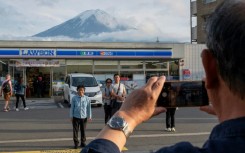 Tourists take pictures of Mount Fuji from opposite a convenience store in the town of Fujikawaguchiko, Yamanashi prefecture