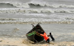 Men push a fishing boat to a sea shore as a preventive measure during rainfall in Kuakata on May 26, 2024, ahead of cyclone Remal's landfall in Bangladesh