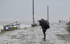 A man uses an umbrella during rainfall in Kuakata on May 26: Cyclones have killed hundreds of thousands of people in Bangladesh in recent decades, but the number of superstorms hitting its densely populated coast has increased sharply