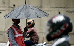 As developing countries urge increases in climate aid, a toll booth worker takes shade under an umbrella during a record heatwave in Delhi