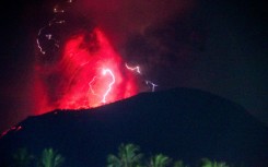 Lightning strikes as lava erupts from the crater of Mount Ibu, as seen from West Halmahera, North Maluku