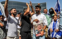 A man holds a picture of freed hostage Almog Meir Jan outside a hospital in central Israel