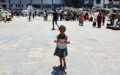 A child carries food at a UN agency for Palestinian refugees (UNRWA) school in Jabalia camp, northern Gaza, where the UN has warned of famine