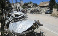 People walk past the rubble of a building that was destroyed by previous Israeli bombardment in the village of Yaroun in south Lebanon