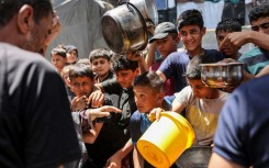 Children queue in Jabalia refugee camp to receive food aid from a kitchen at the Abu Zeitun school run by UNRWA, the UN agency for Palestinian refugees