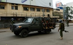 A patrol car from the Kenya Defence Forces drives past policemen during fresh demonstrations