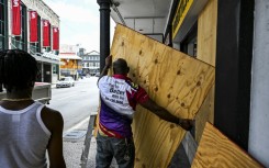 A man boards up a shop window as people prepare for the arrival of Hurricane Beryl in Bridgetown, Barbados