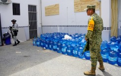 Military personnel stand close to stockpiles of water before Hurricane Beryl's arrival in Tulum