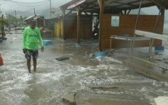 A man screws a board onto the window of a shop in preparation for the arrival of Hurricane Beryl in Bridgetown, Barbados on June 30, 2024