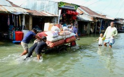 People push a handcart carrying supplies through the flood at Fenchuganj in Sylhet on July 3, 2024