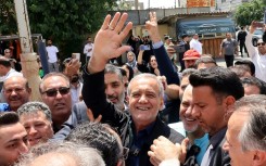 Reformist candidate Masoud Pezeshkian waves to supporters outside a polling station in Tehran