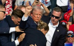 Republican candidate Donald Trump is seen with blood on his face surrounded by Secret Service agents as he is taken off the stage