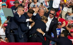 Trump is seen with blood on his face as Secret Service rush him off the stage