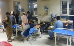 Men sit next to injured children as they receive treatment at a hospital in Jalalabad 