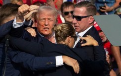 Republican US presidential candidate Donald Trump is surrounded by Secret Service agents as he is taken off the stage after an assassination attempt on July 13, 2024, at a rally in Pennsylvania