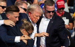 Secret Service agents shield former president Donald Trump as he is escorted off the stage following an attempted assassination