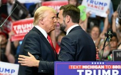 Republican nominee Donald Trump, wearing a new bandage on his ear after an attempted assassination, greets running mate J.D. Vance at a rally in Grand Rapids, Michigan