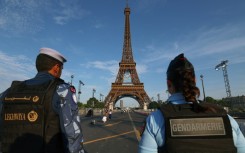 A French policewoman and a Qatari policeman stand guard near the Eiffel Tower as security preparations step up for the Paris Olympics