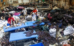 Workers sort through the remains of a garment factory torched during the protests