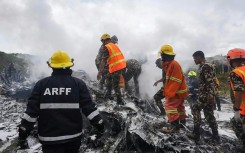 Rescuers and army personnel stand at the site after a Saurya Airlines' plane crashed during takeoff at Tribhuvan International Airport in Kathmandu on July 24, 2024