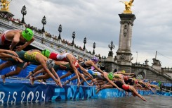 Triathletes dive into the River Seine at the start of the Olympic triathlon