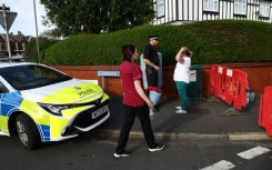 A woman arrives with a floral tribute to pay her respects at Hart Street in Southport, northwest England, on July 29, 2024, following a knife attack