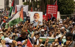 Demonstrators lift placards with Ismail Haniyeh's image and Palestinian flags during a rally in Rabat, Morocco