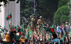 Bangladeshi protesters gather near the gates of ousted premier Sheikh Hasina as soldiers watch: Hasina, 76, fled the country by helicopter