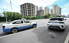 A regular taxi overtakes a driverless one in Wuhan, home to one of the world's largest robotaxi networks